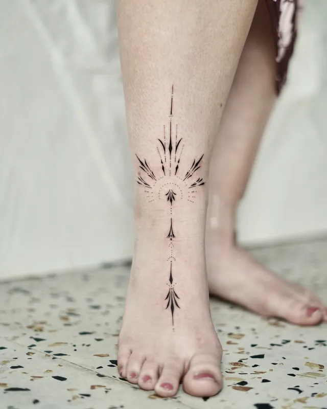 Fine line ornamental tattoo running down the front of the ankle and foot