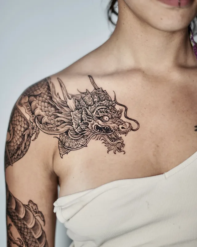 Japanese dragon head across the shoulder and collarbone in black and grey