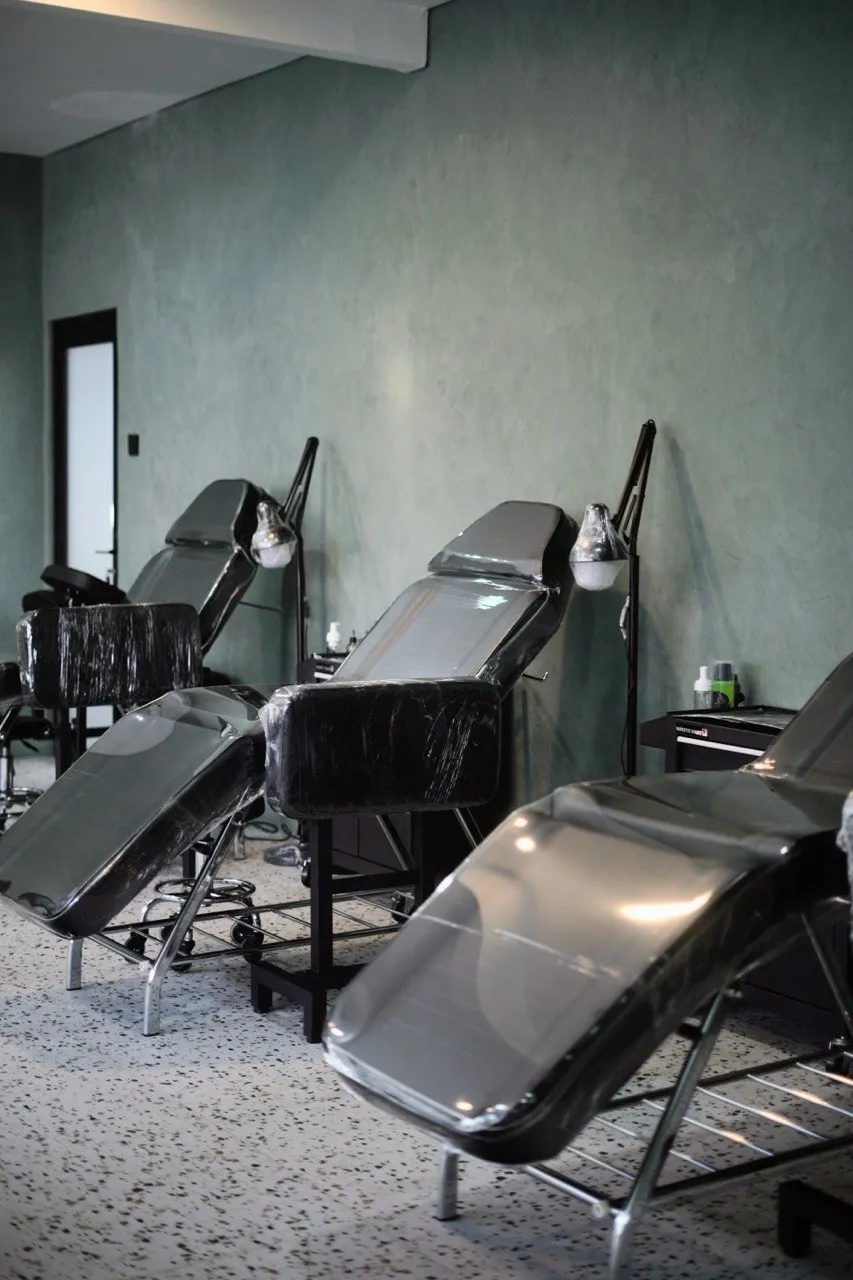 Row of tattoo beds with lamps along the green wall at Mason's Ink Raya Taman